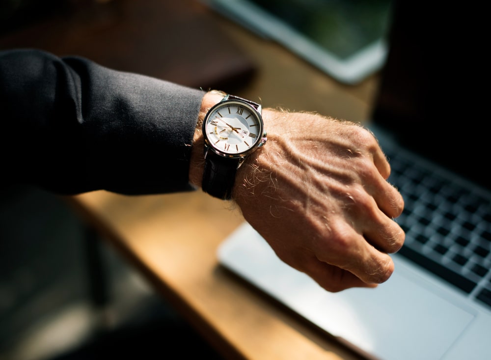 Homme d'affaires portant une montre classique à cadran blanc dans un environnement professionnel, exemple de montres originales masculines