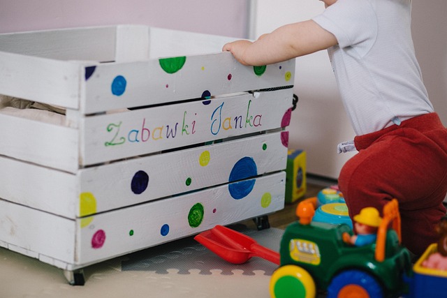 Un jeune enfant interagit avec une caisse à jouets colorée, propice à l'éveil musical.