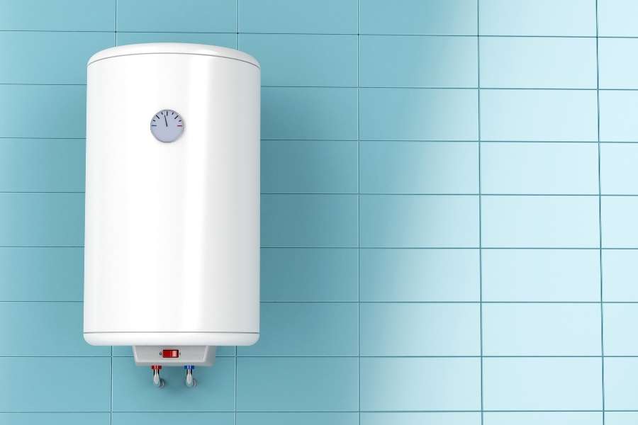 Un chauffe-eau électrique blanc fixé sur un mur carrelé bleu pour détartrer un chauffe-eau électrique.