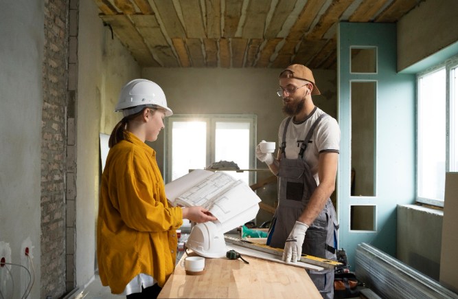 Architecte et artisan consultant des plans sur un chantier de rénovation, illustrant l'estimation des travaux face à la baisse prix passoire thermique DPE France.